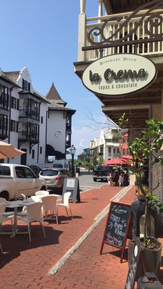 the outside of a restaurant with tables and chairs on the side walk next to it