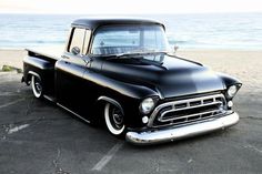 an old black pickup truck parked on the beach