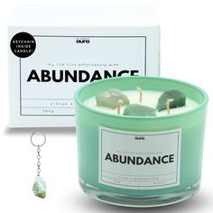 an abundance candle and keychain with the box behind it