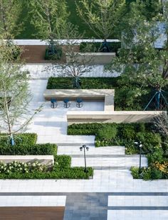 an aerial view of a park with benches, trees and plants on the sides of it