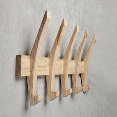 a wooden coat rack with four coats hanging on it's sides and three hooks attached to the wall