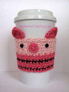 a coffee cup cozying with a pink and black knitted face on the side