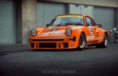 an orange race car parked in front of a garage