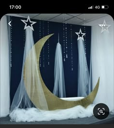 an image of a room decorated with white stars and moon decorations on the wall, along with sheer curtains