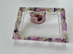 a glass vase sitting on top of a white table next to a flowered bowl