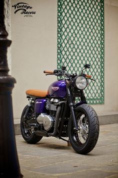 a purple and black motorcycle parked on the street next to a lamp post in front of a building