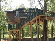 a tree house in the woods with stairs leading up to it's second story