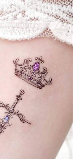 a tattoo on the side of a woman's stomach with a tiara and cross