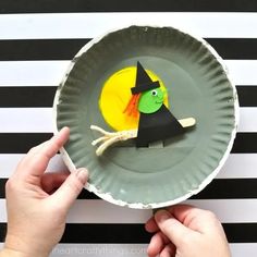 a paper plate with a witch on it and a hand holding up the paper plate