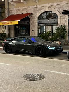 a black sports car is parked on the side of the road in front of a building