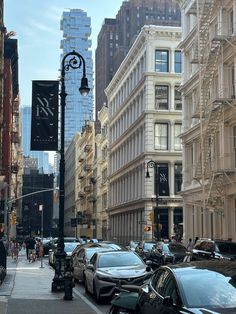 cars are parked on the side of the street in front of tall buildings and skyscrapers