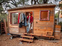 a man standing in the doorway of a tiny house with clothes hanging out to dry