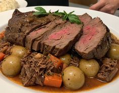 a white plate topped with meat, potatoes and carrots on top of a table