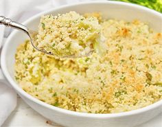 a spoon full of broccoli casserole in a white bowl on a table