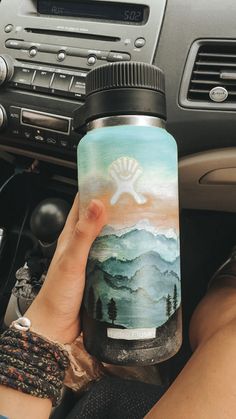 a person is holding a water bottle in their hand while sitting on the dashboard of a car