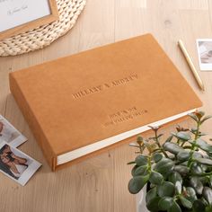 a brown book sitting on top of a wooden table next to a potted plant