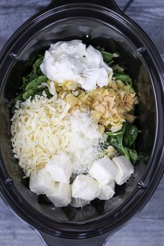 the food is being prepared in the crockpot with cheese, spinach and other ingredients