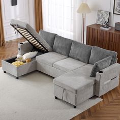 a sectional sofa with an ottoman underneath it in a living room next to a window