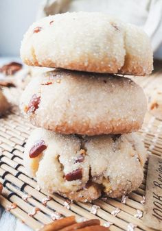 three cookies stacked on top of each other with nuts scattered around them and a bottle of milk in the background