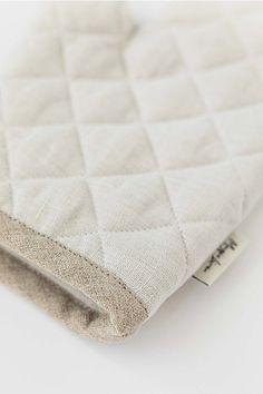 a close up of a white quilted material on a white surface with a tag