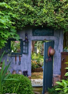 an outdoor garden with green plants and potted plants on either side of the door