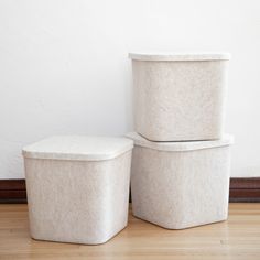 two white storage containers sitting next to each other on top of a hard wood floor