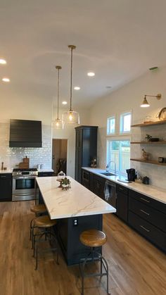 a large kitchen with wooden floors and black cabinets