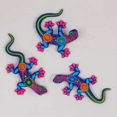 three colorful geckos sitting on top of a white table next to each other