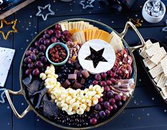 a platter filled with cheese, crackers and grapes