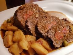 a white plate topped with meat and potatoes