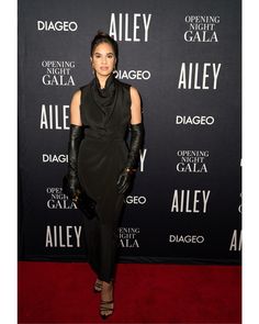 a woman in black dress and leather gloves on red carpet at an allegge event