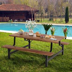 a picnic table with food on it next to a pool