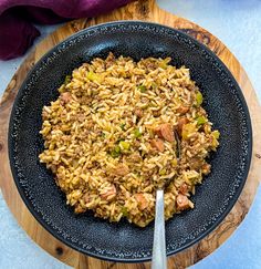 a plate full of rice and meat on a wooden board with a fork in it