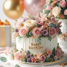 a birthday cake decorated with pink and white flowers on a table next to gold foil balloons