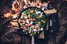 a skillet filled with food sitting on top of a fire