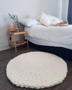 a cat laying on top of a white rug next to a bed in a bedroom