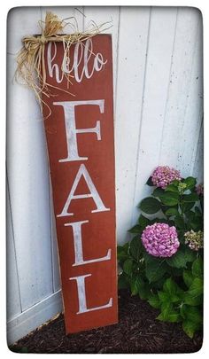 a wooden sign that says hello fall next to some flowers