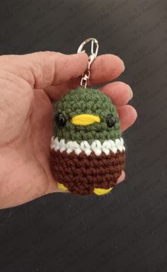 a small crocheted bird keychain is in someone's hand