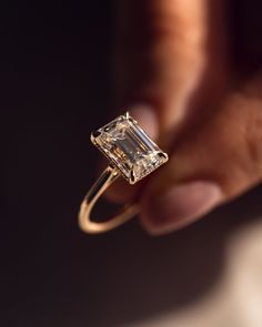 a woman's hand holding an engagement ring with a large diamond in the center