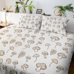 a bed with mushrooms printed on it in a white and brown bedroom area next to a potted plant