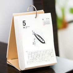 a calendar sitting on top of a wooden table next to a pen and paper clip