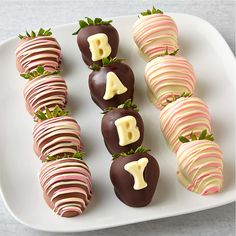 chocolate covered strawberries are arranged on a white platter with the letter e painted on them