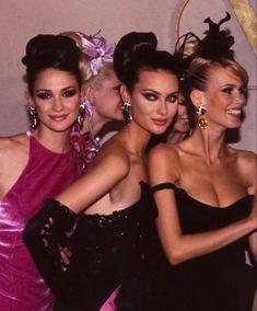 three women in evening gowns posing for the camera with their arms around each other