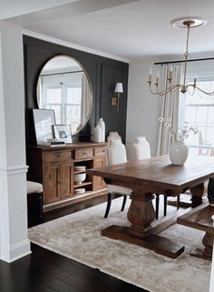 a dining room table and chairs in front of a large mirror with a chandelier