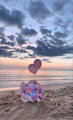 some balloons and flowers in the sand at the beach