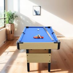 a pool table in the middle of a room with wood flooring and large windows