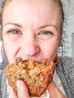 a close up of a person holding food in front of her face and eating it