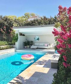 a pool with an inflatable mattress sitting next to it and flowers around the pool