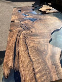 a table made out of wood and glass in the sun with water running down it