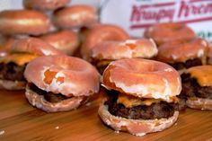 mini hamburgers with cheese on them sitting on a cutting board next to a bag of krispy kreme doughnuts